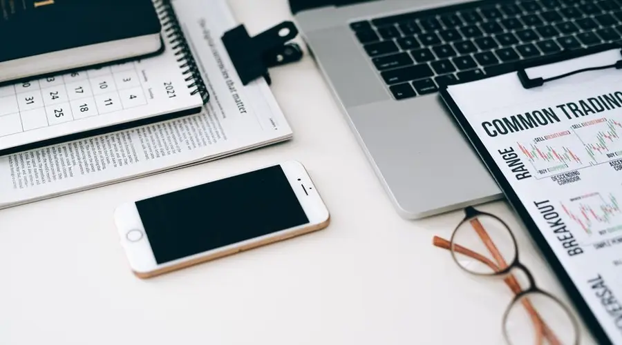 A well-organized office desk setup with finance documents, digital devices, and glasses.