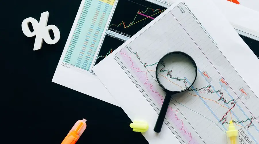 High-angle view of financial charts, showcasing stock market analysis with magnifying glass and highlighters.