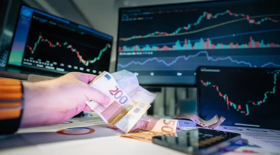 Close-up of euro banknotes with financial market graphs in the background, depicting finance and investment themes.