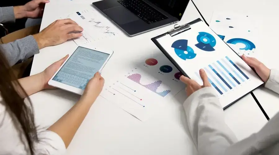 Team analyzing financial charts and digital reports during a business meeting.