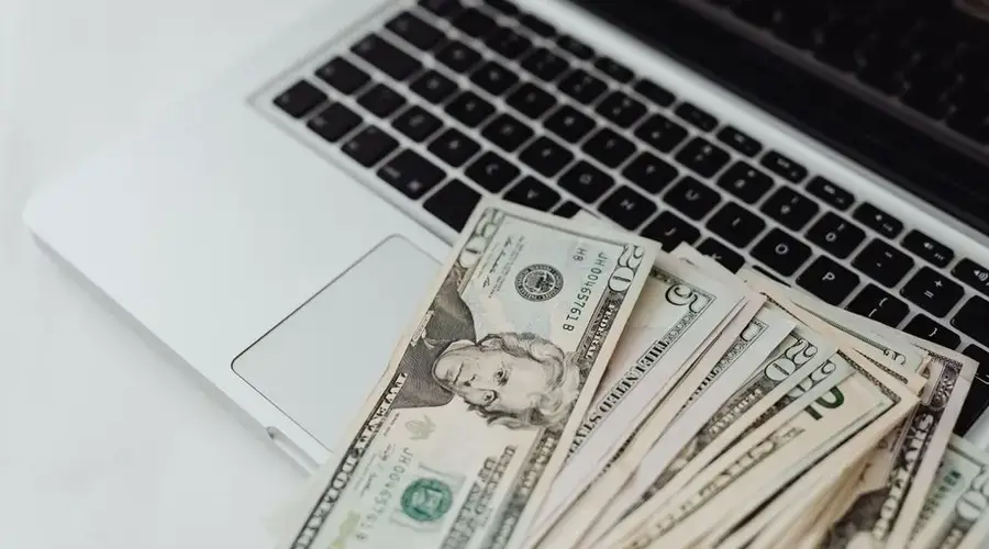 Close-up of US dollar banknotes on a laptop keyboard symbolizing online finance and technology.