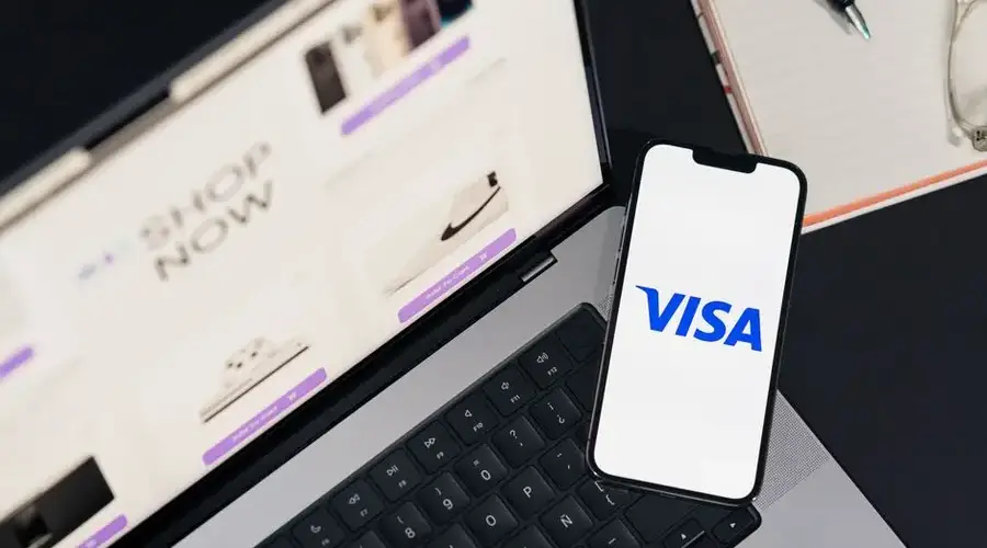 Smartphone displaying VISA on a laptop for online shopping experience.