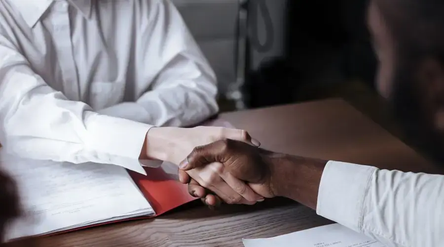 Close-up of a diverse business handshake over documents, symbolizing agreement and collaboration.