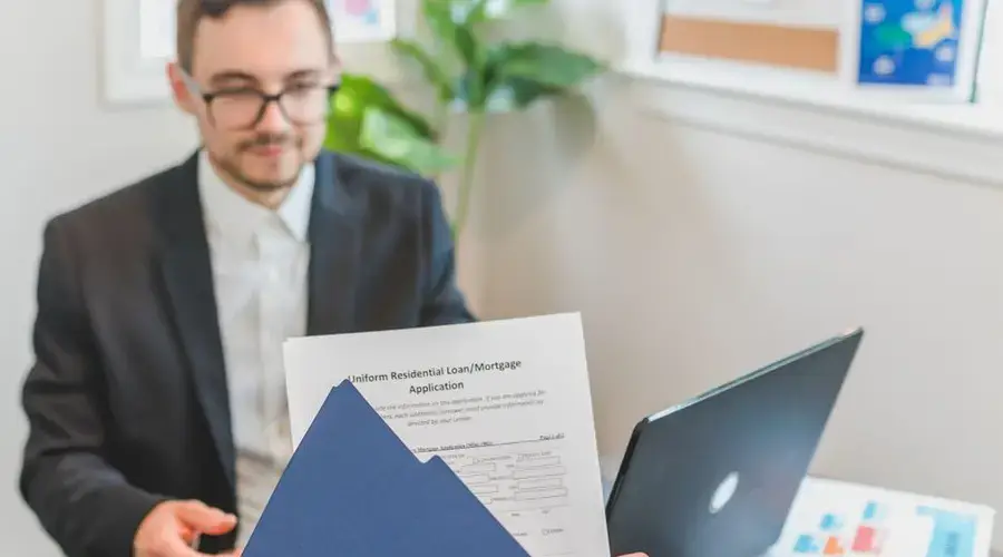 Mortgage broker and client discussing loan application with documents on table.