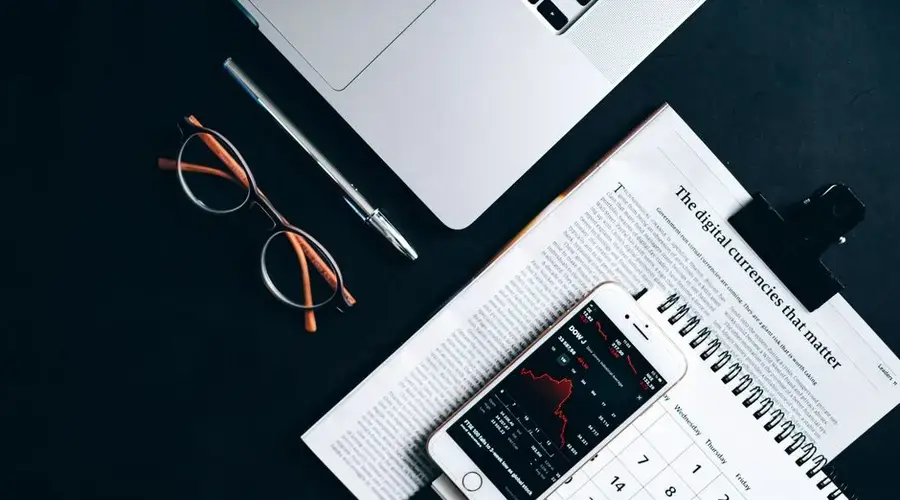 Flat lay of electronic devices and financial documents showcasing digital currency analysis.