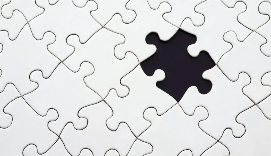 Close-up of an incomplete white puzzle with one missing piece, symbolizing challenge and strategy.