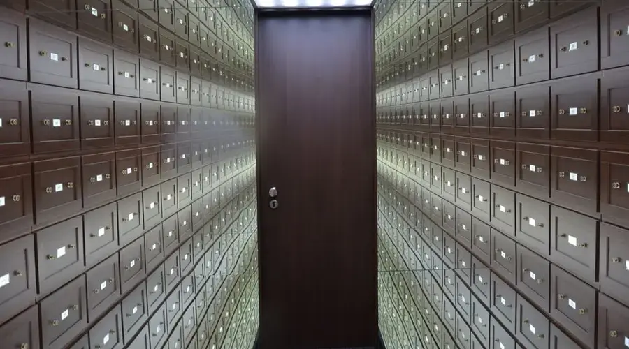 Wooden lockboxes line the walls of a modern, secure vault with a central wooden door.