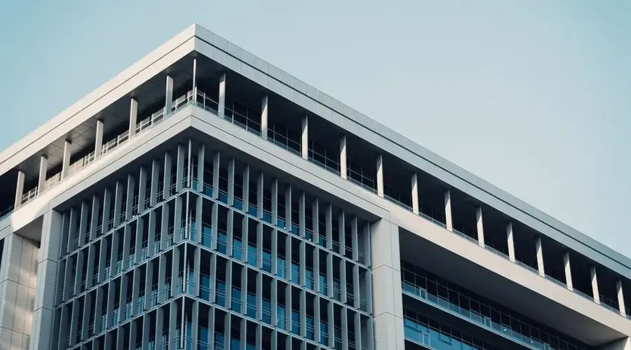 Contemporary office building with a futuristic glass facade reflecting the sky.