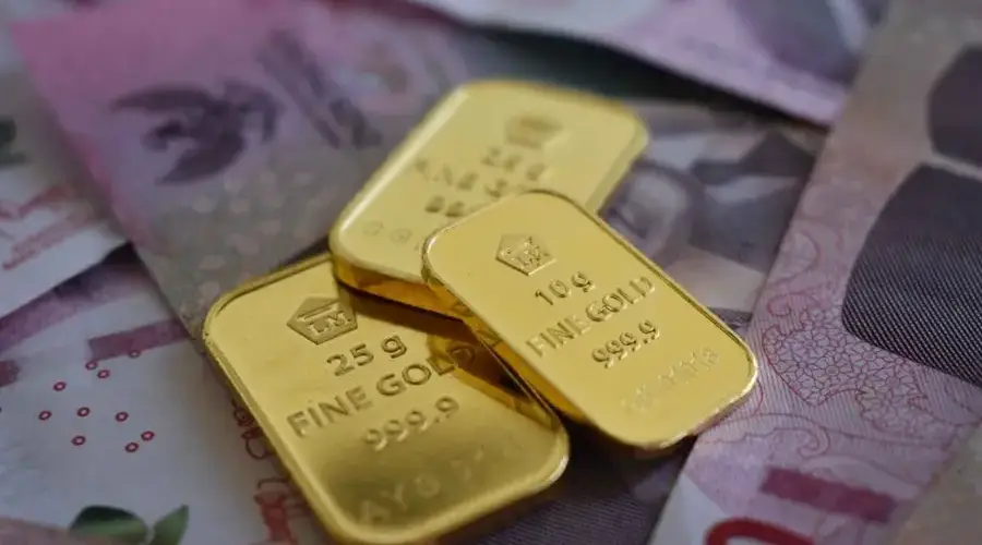 Detailed gold bars layered over Indonesian currency, highlighting wealth and investment.