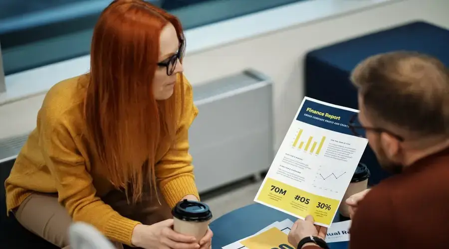 Two colleagues reviewing a financial report in a modern office setting.