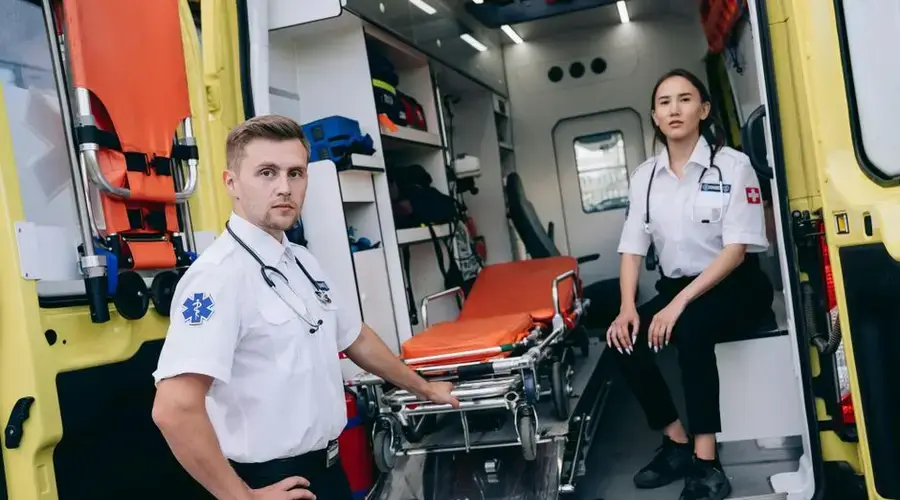 Paramedics prepare for an emergency with medical equipment in an ambulance.