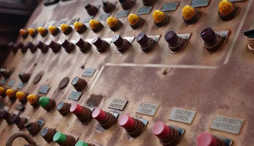 Vintage control panel with colorful buttons and industrial labels.