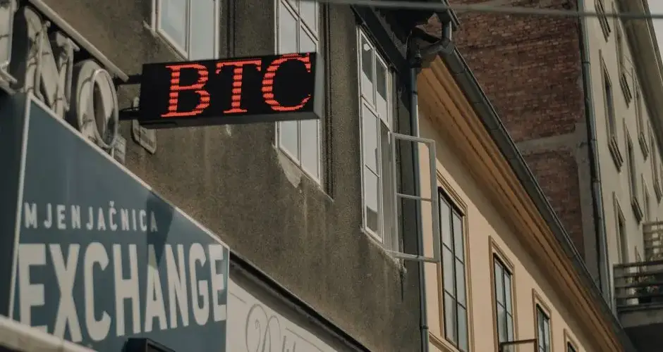 Exterior of a building featuring a prominent BTC and exchange sign, indicating a cryptocurrency location.