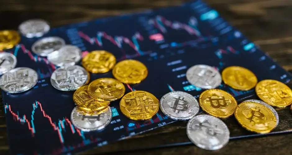 Gold and silver Bitcoin coins on financial graph, symbolizing cryptocurrency trading and digital currency wealth.