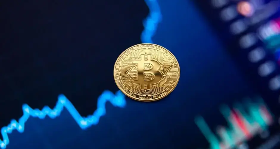 Bitcoin coin on background of monitor with graph of changes in cryptocurrency rates