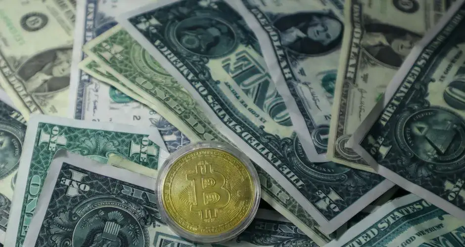 Close-up of Bitcoin cryptocurrency coin on a pile of US dollar banknotes, symbolizing finance and digital currency.