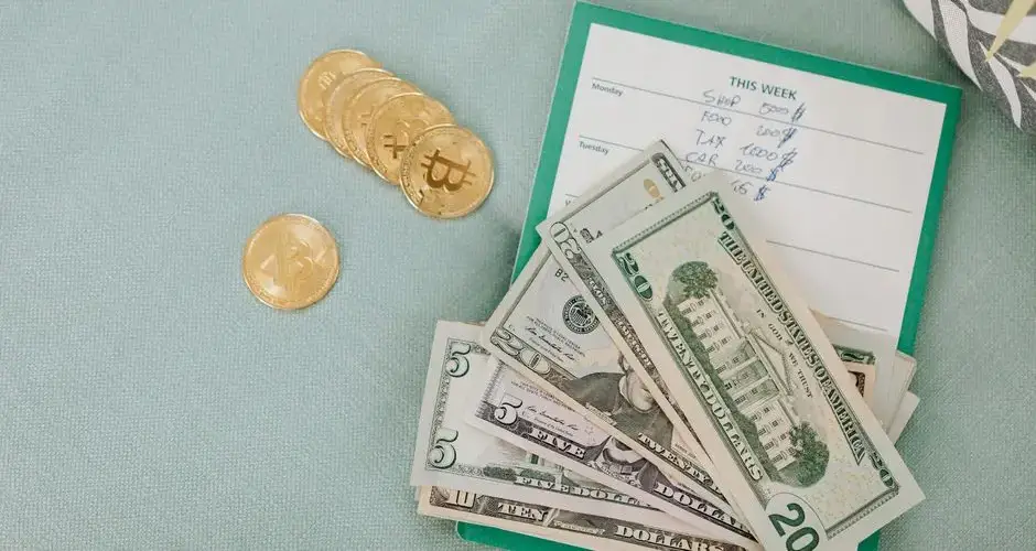 Close-up of U.S. dollars and Bitcoin coins placed on a weekly budget planner, symbolizing modern finance.