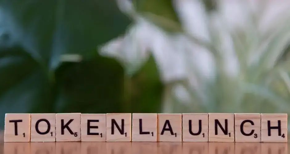 Scrabble tiles spelling 'Token Launch' on a vibrant green background.