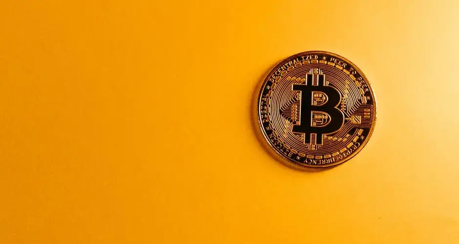Close-up of a Bitcoin cryptocurrency coin on a vibrant yellow background, symbolizing digital money.