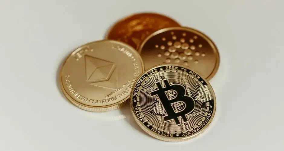 Cryptocurrency coins representing Bitcoin, Ethereum, and Cardano on a white background.