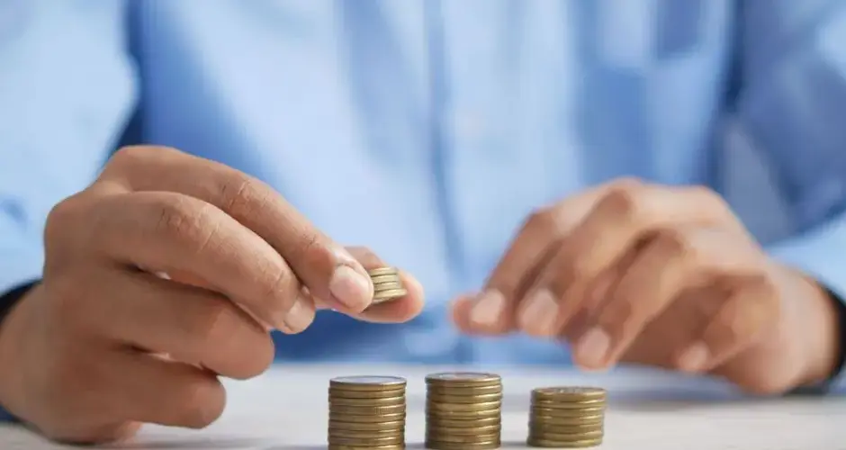 Close-up of hands stacking gold coins, symbolizing financial growth and savings.