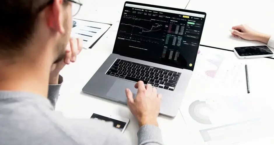 Business professional analyzing stock market data on a laptop for investment insights.