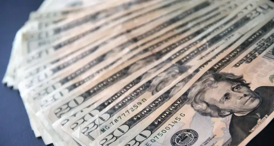Close-up shot of multiple US twenty dollar bills spread out, symbolizing wealth and finance.