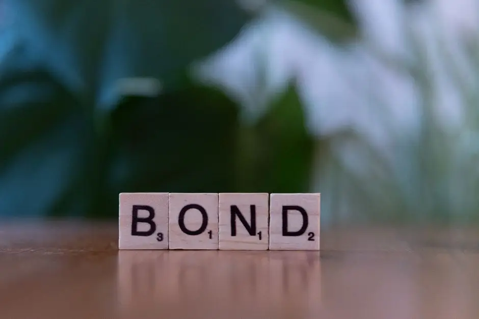 Scrabble tiles spelling 'Bond' on a wooden table with a blurred green background.