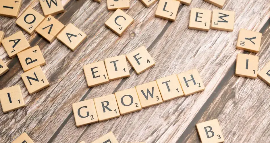 Wooden tiles spelling ETF growth on a wooden surface, symbolizing investment strategy.