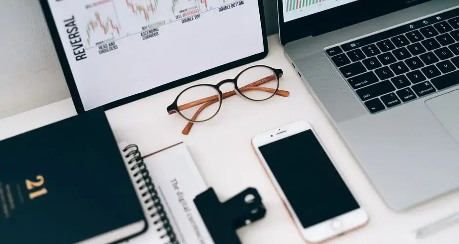 A modern work desk setup featuring electronic devices and financial graphs for productivity.