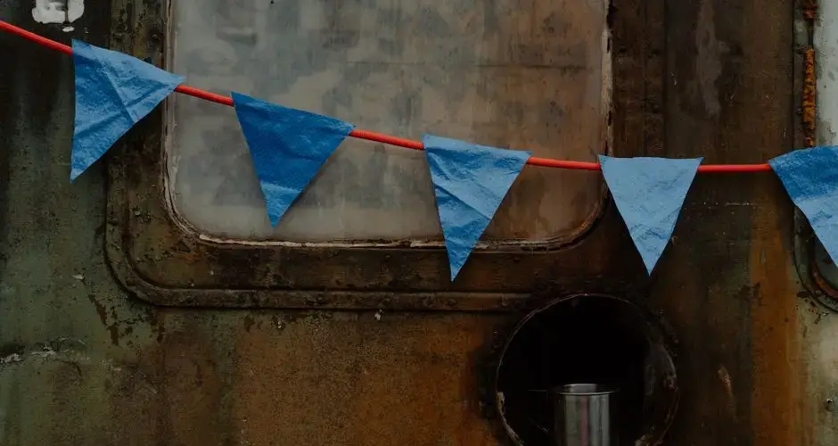 A weathered metal surface adorned with blue triangular garland flags and a metal cup.