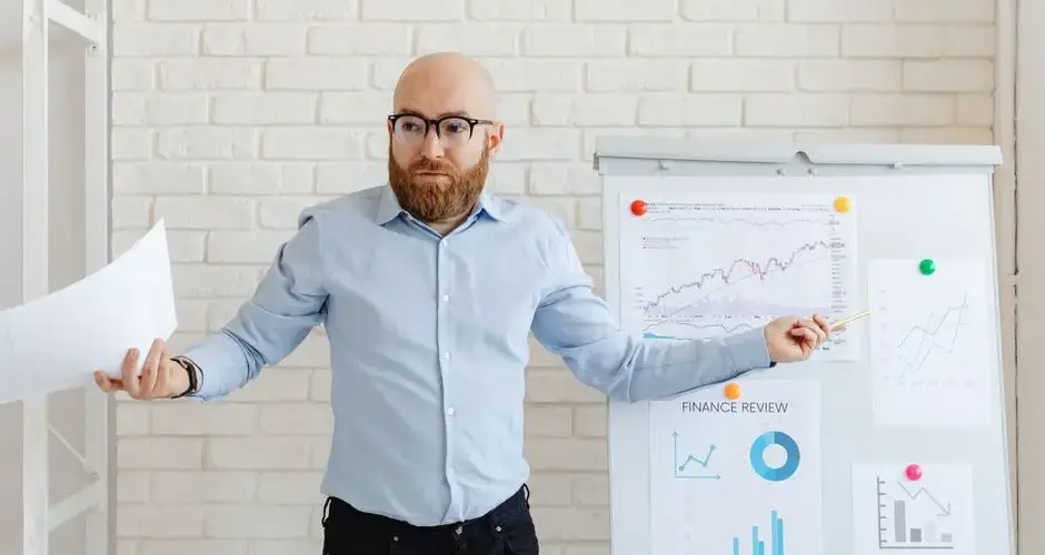 Confident businessman presents financial data on charts in a modern office setting.
