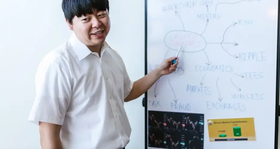 A professional explaining cryptocurrency concepts on a whiteboard during a seminar.