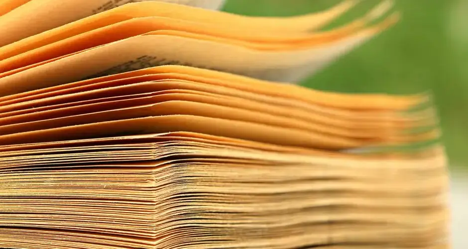 Macro shot of aged book pages with a blurred green background, highlighting texture and detail.