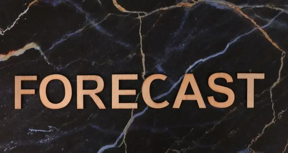 The word 'FORECAST' in wooden letters on a dark marble background.