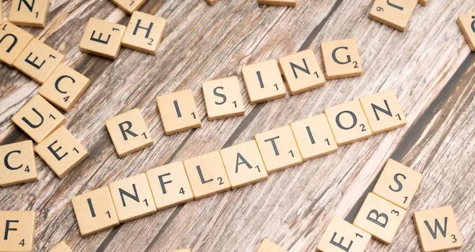 Wooden letter tiles spell 'rising inflation' symbolizing economic concerns.