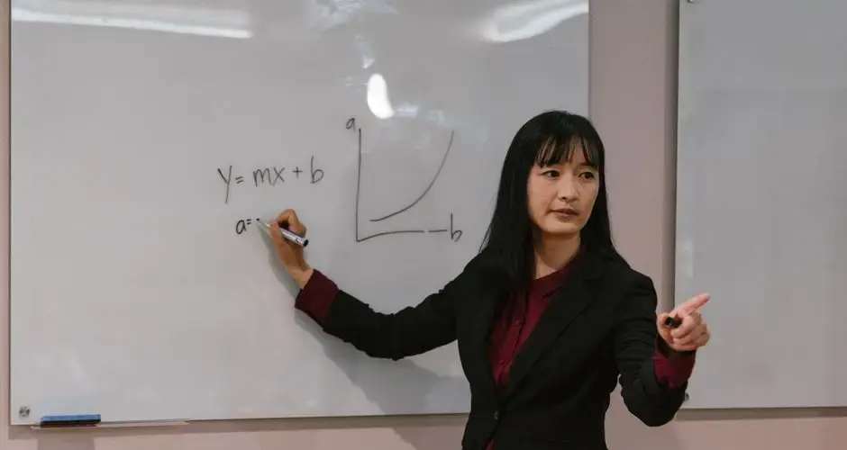 Female teacher explaining mathematical graph on whiteboard during a lesson.