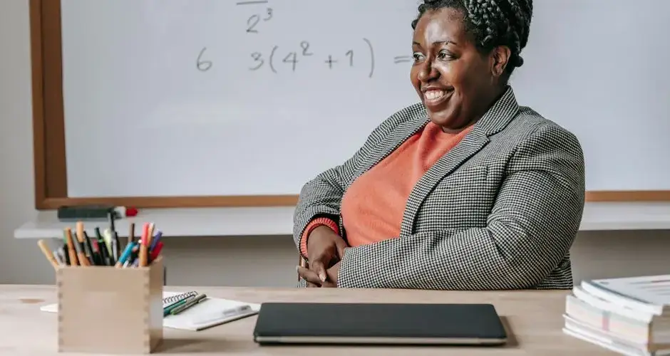 Happy African American female smiling and preparing for lesson in classroom with whiteboard