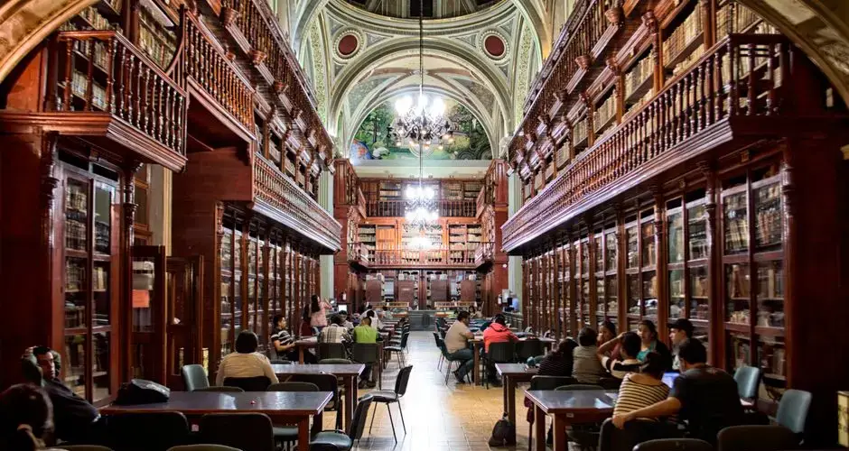 Elegant library with people studying, surrounded by wooden shelves and classical architecture.