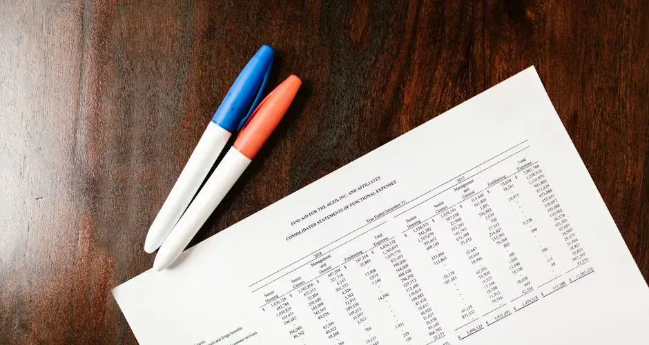 A financial statement on a wooden desk with colorful pens, ideal for accounting themes.