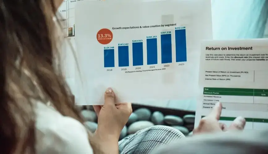 Person analyzing financial graphs and ROI reports, focusing on investment growth.