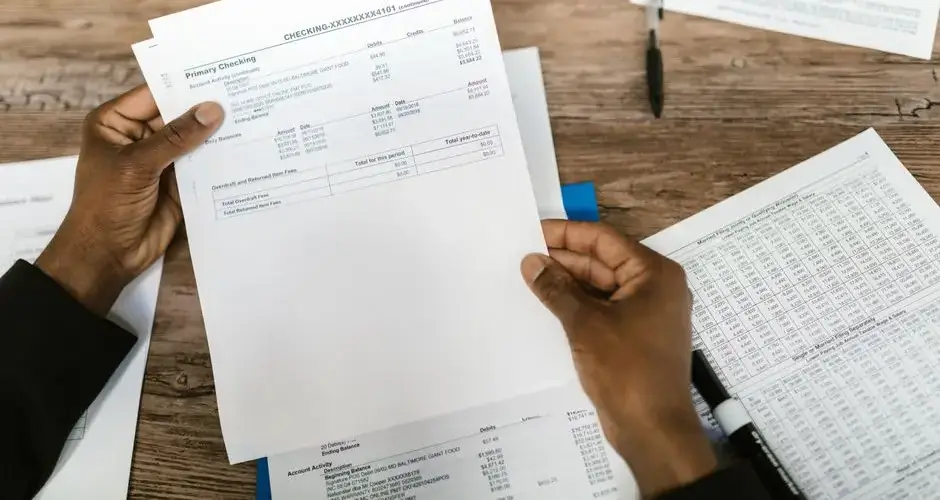 Hands holding financial papers for tax preparation and analysis.