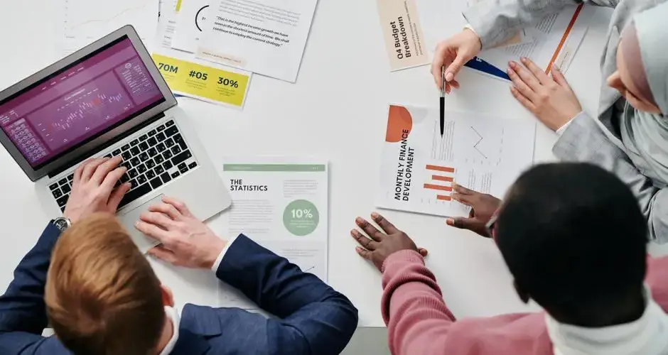 Business meeting with professionals discussing financial reports and graphs at a work desk.