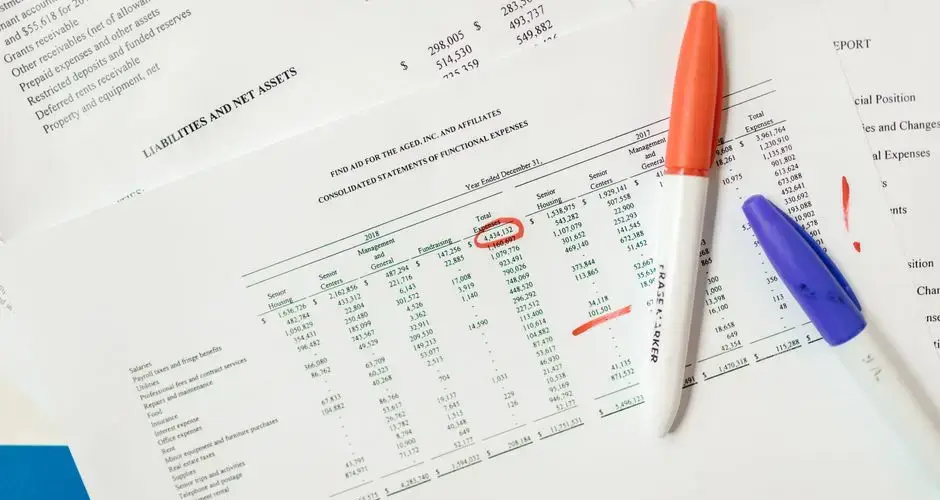 Close-up of financial documents with highlighted figures and marker pens.