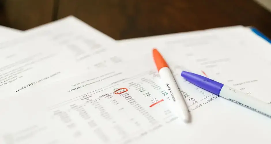 Close-up of financial documents with pens highlighting important data points.