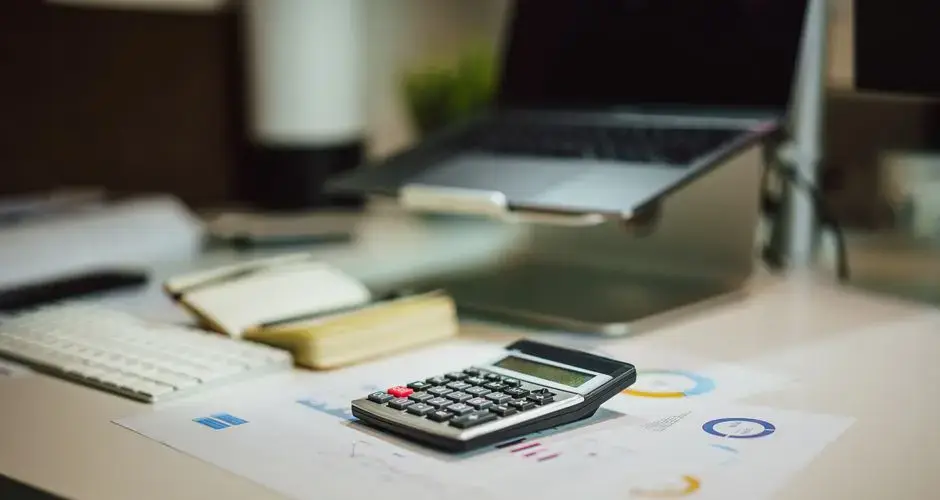 A modern workspace with a laptop, calculator, and documents on a desk, perfect for finance tasks.