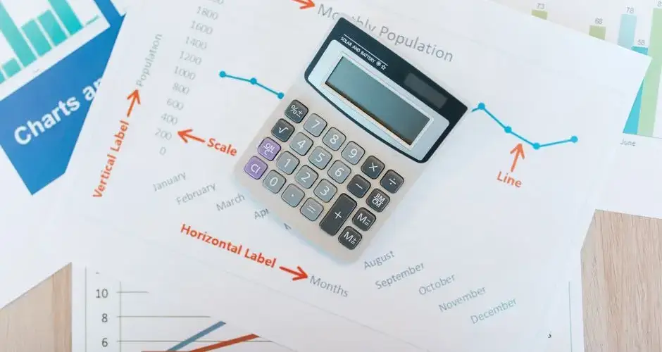 Calculator placed on financial graphs and reports showcasing data analysis and business documentation.