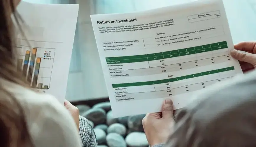 Close-up of two individuals analyzing financial documents related to return on investment.