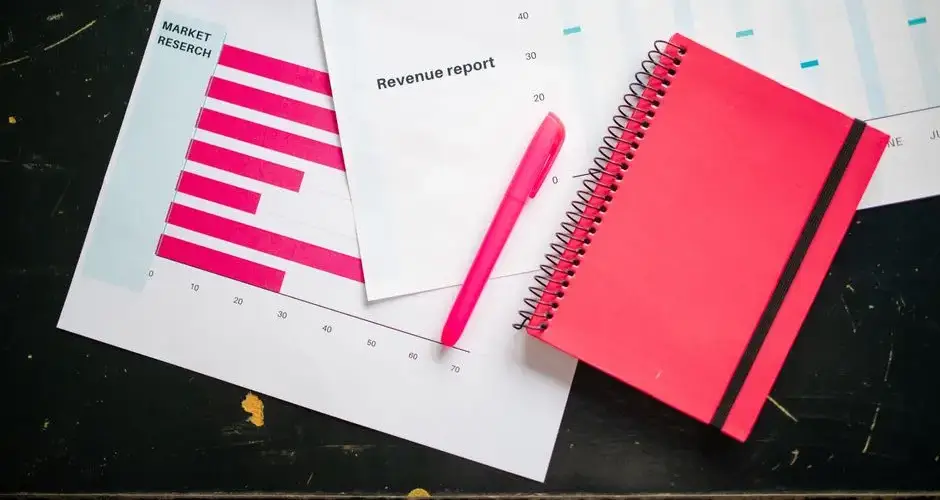 Overhead shot of a desk with charts, a red notebook, and a pen for business analysis.