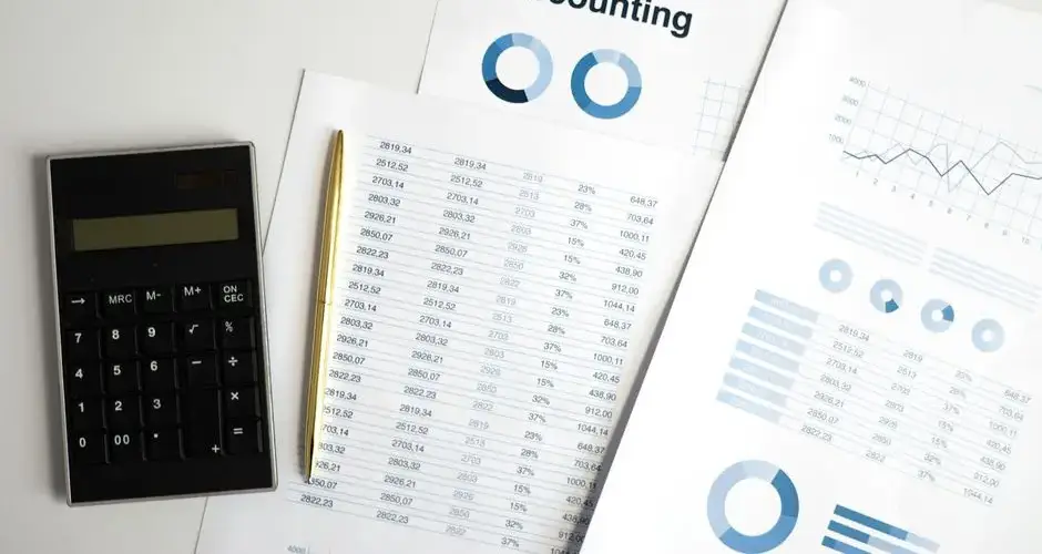 Calculator and accounting documents with charts on a workspace.